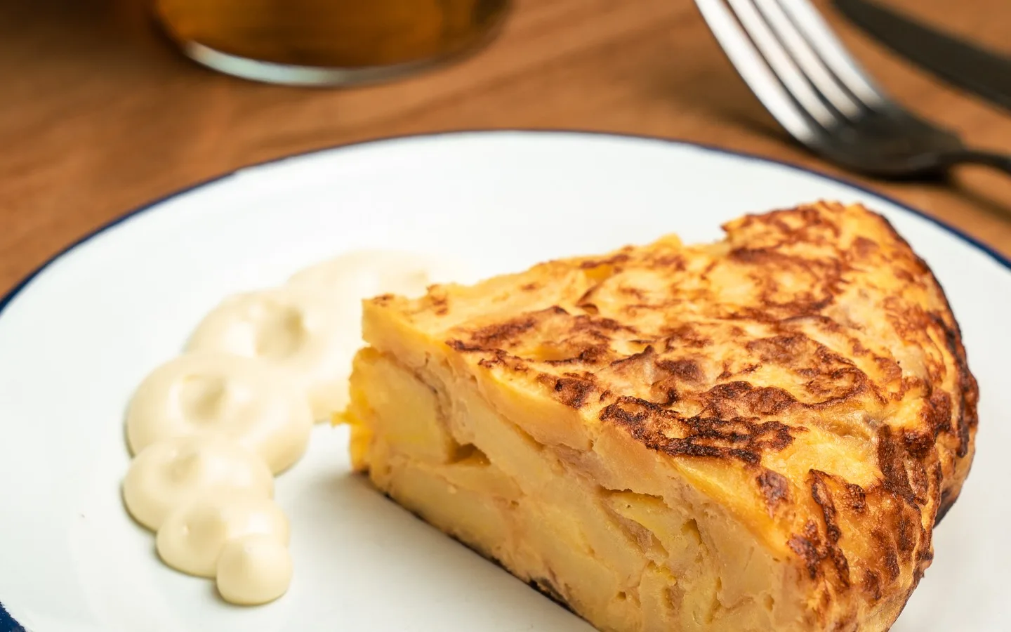 Una porción de tortilla casera con alioli y una cortada